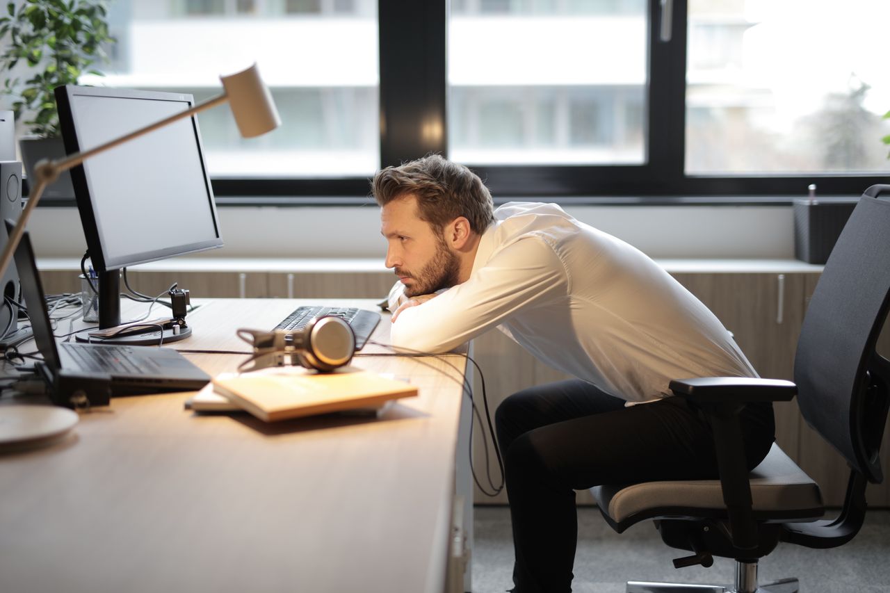 Mann mit schlechter Sitzhaltung vor einem Computer im Büro